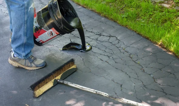 Focus On Exceptional Quality Asphalt Driveway Replacement North Shore | Asphalt Driveway Auckland Worker applying sealant to cracked pavement as part of high-quality Asphalt Driveway Replacement North Shore by Asphalt Driveway Auckland.